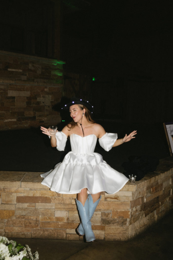 bride sitting on the stage enjoying a drink with her cowboy hat for her wedding party prop