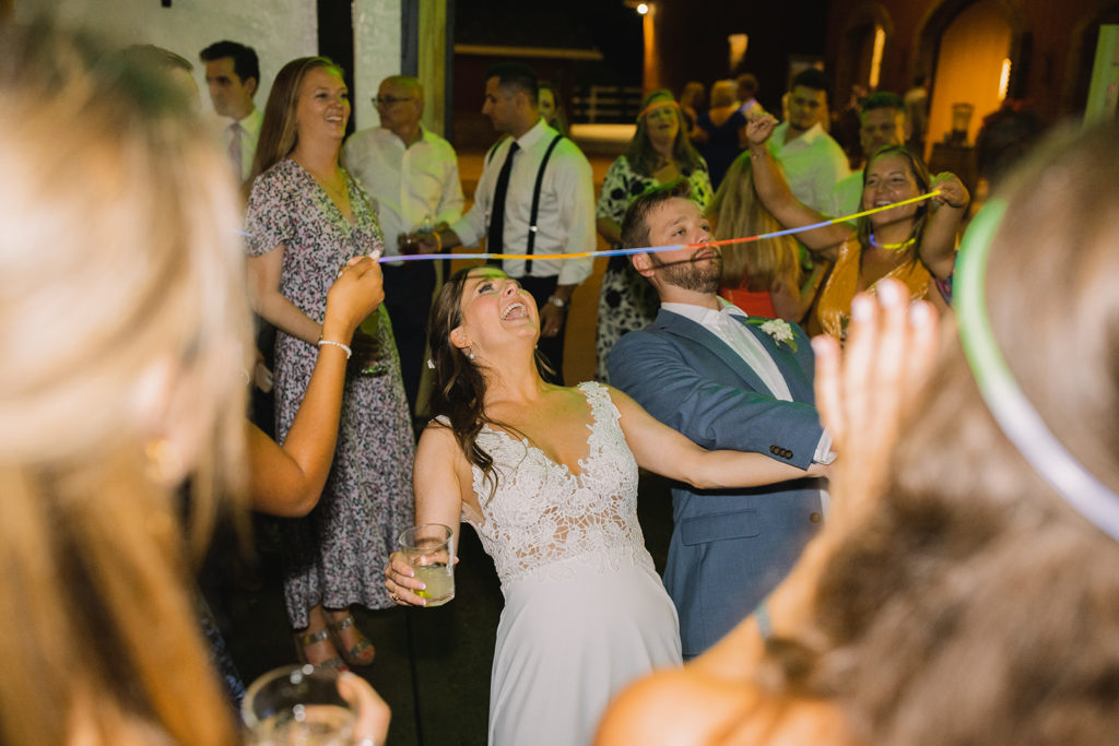 couple limboing with glow sticks as their wedding party prop